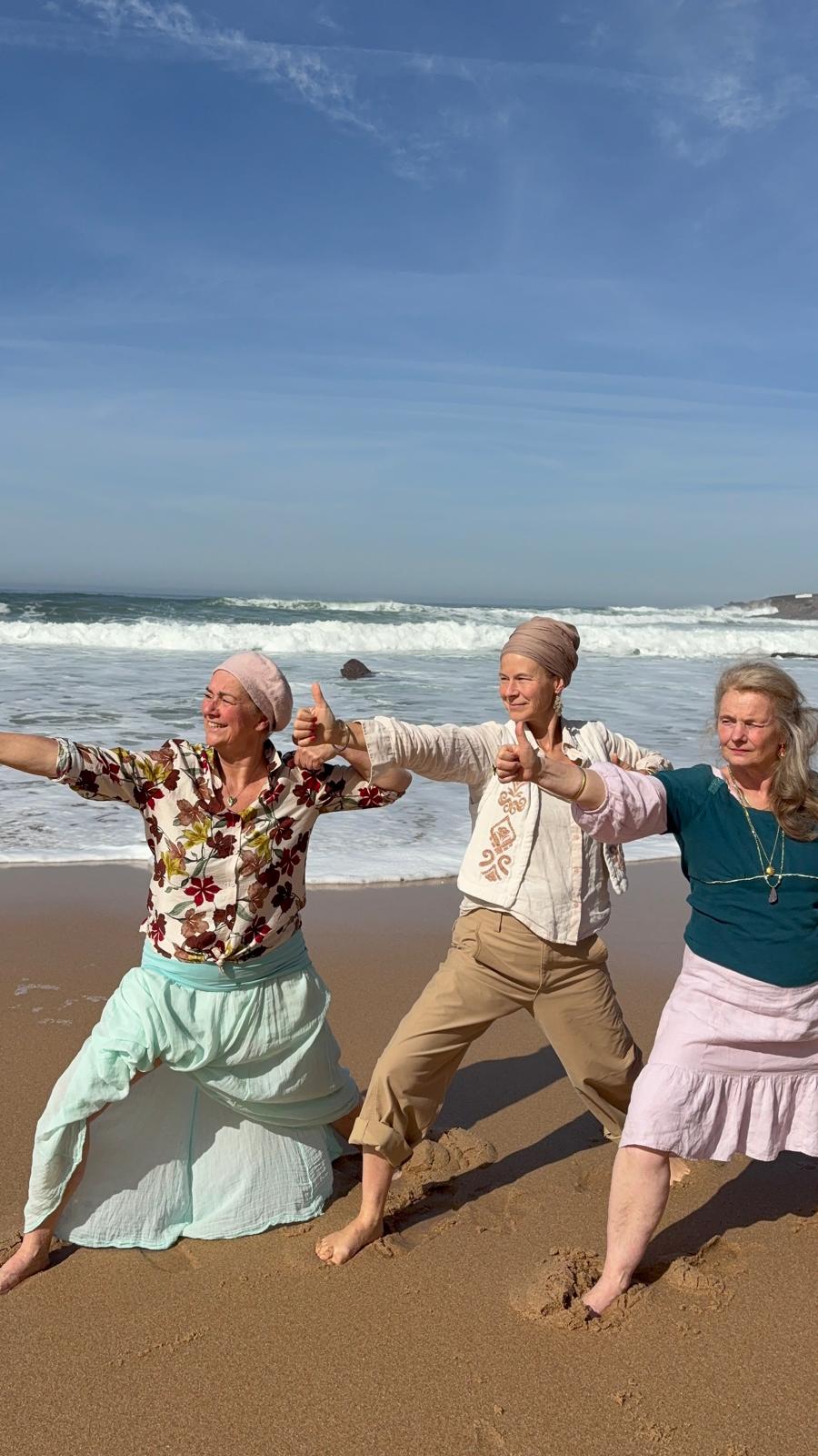 Drie vrouwen op het strand tijdens een yogahouding